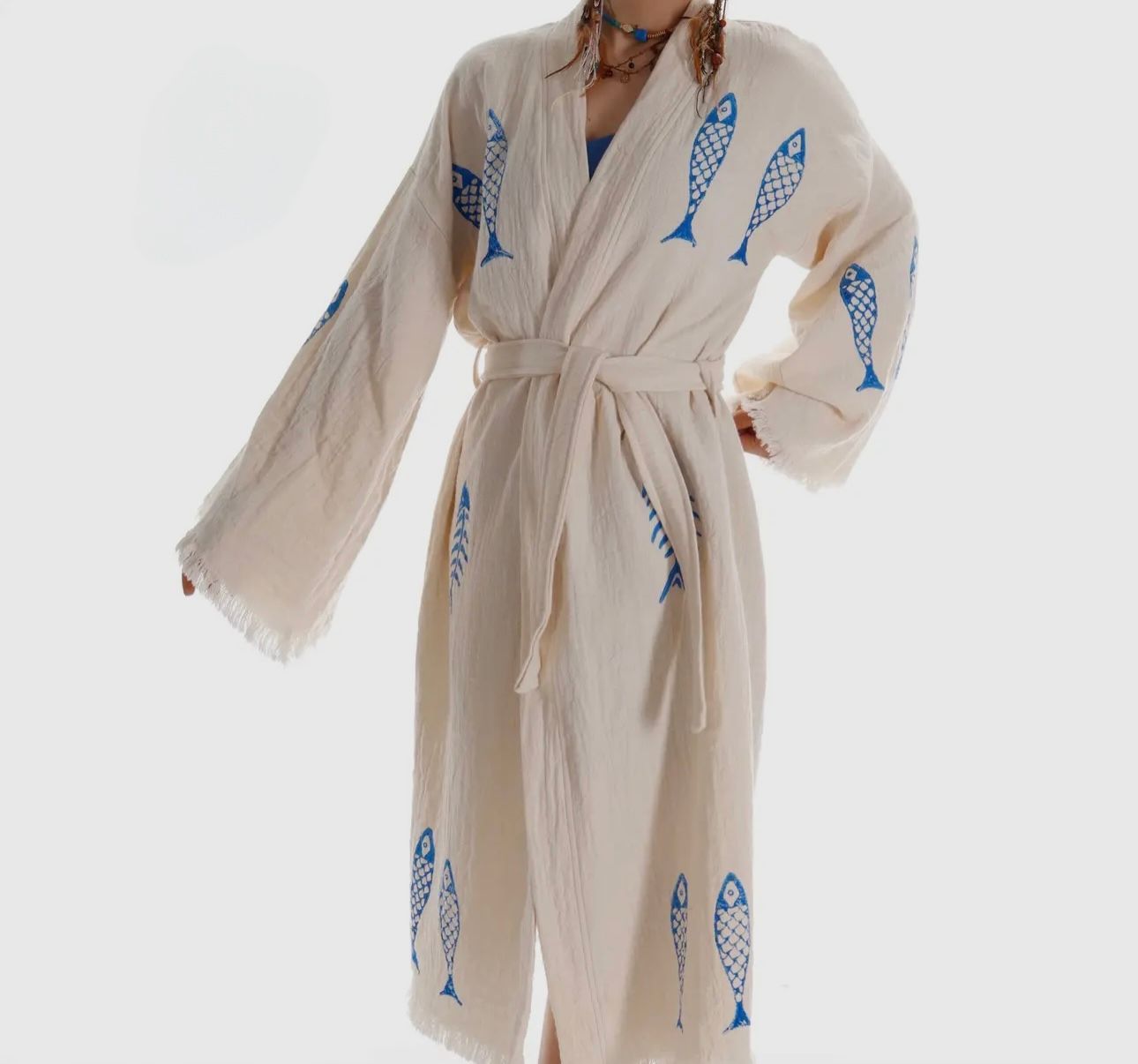 A woman is wearing a white robe with blue fish embroidered on it