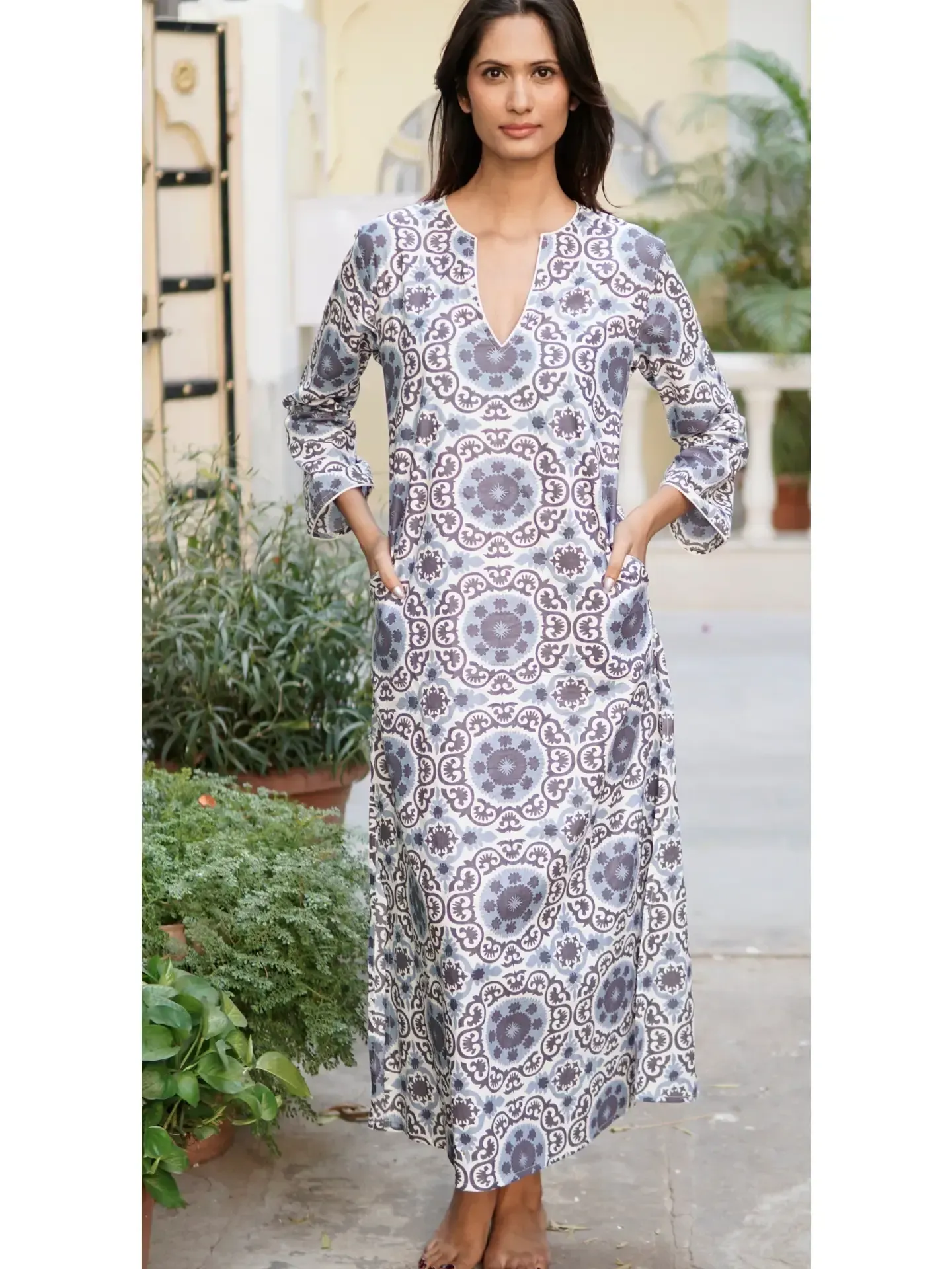 A woman is wearing a long white dress with a floral pattern.