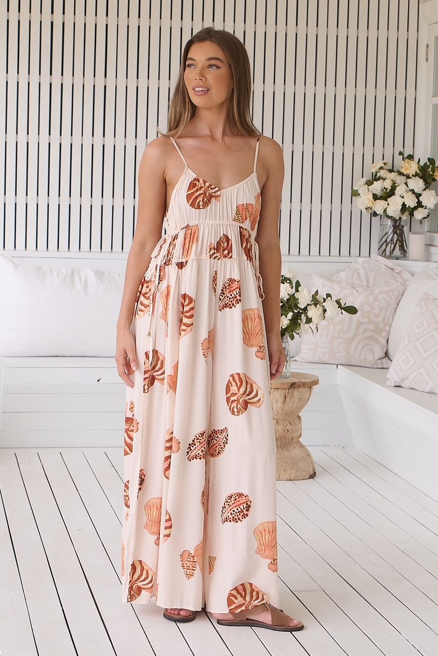 A woman is wearing a long white dress with leaves on it.