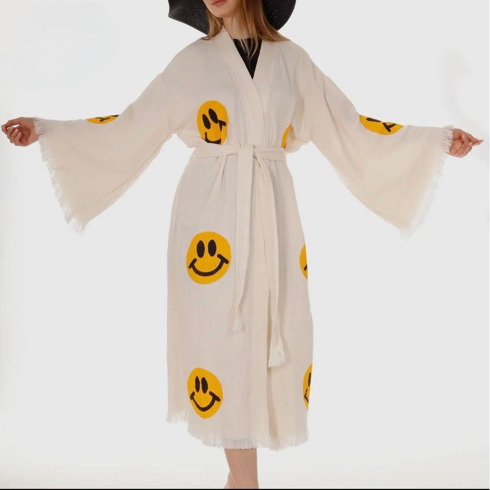 A woman wearing a white robe with smiley faces on it