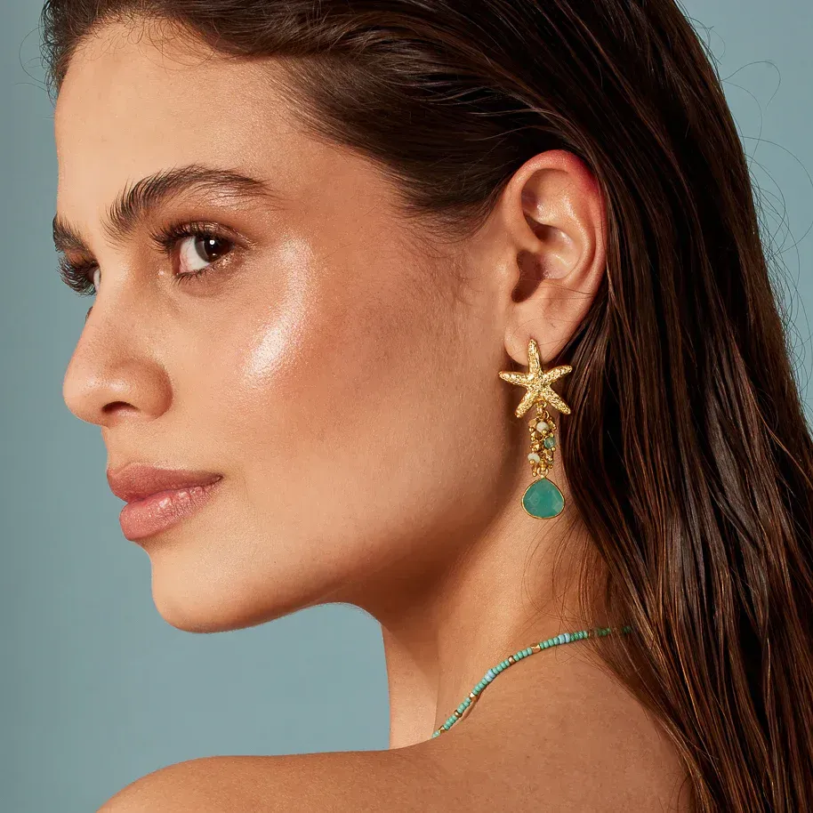 A woman wearing a pair of earrings with a starfish on them