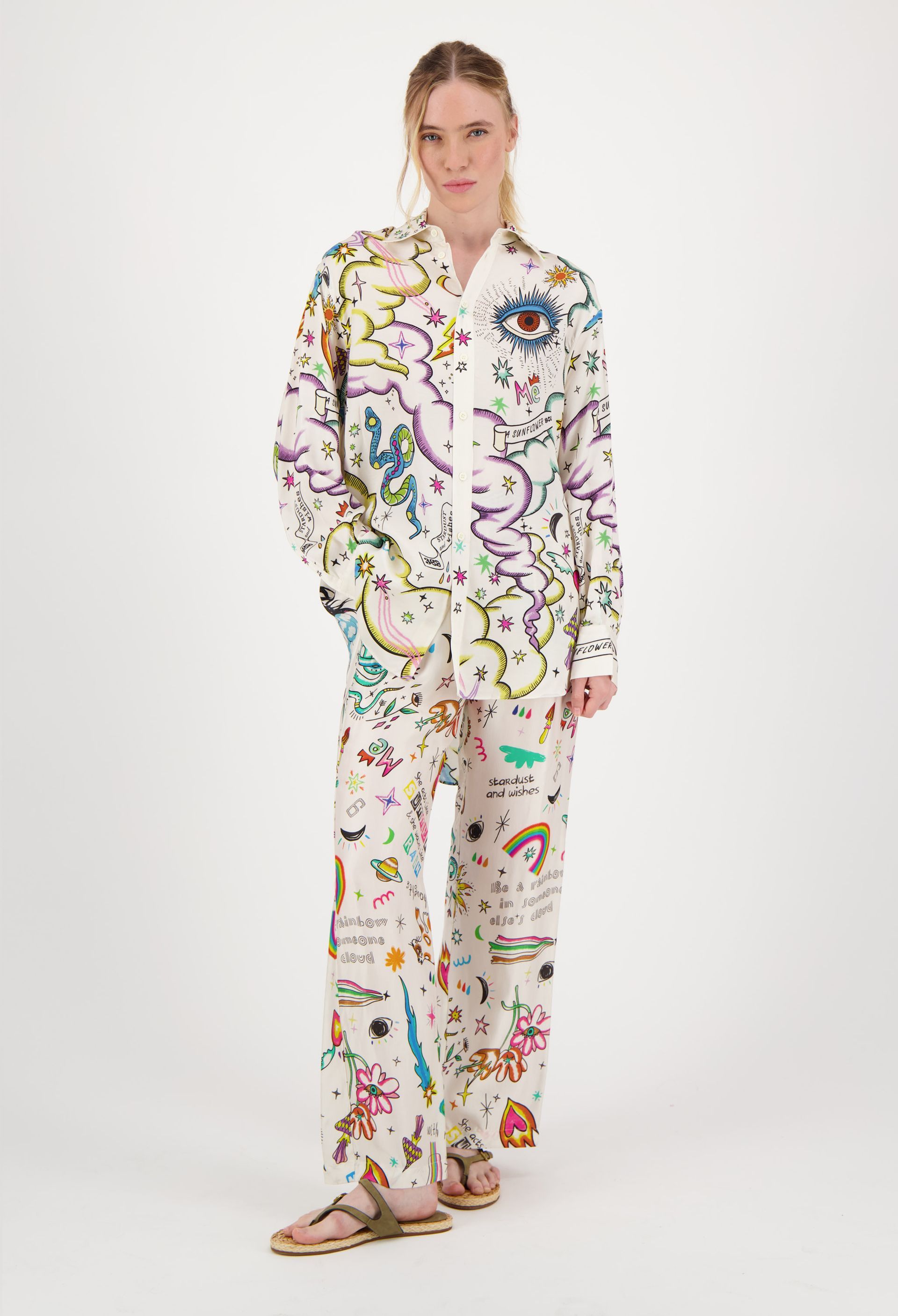 A woman is wearing a white shirt and pants with a colorful pattern.