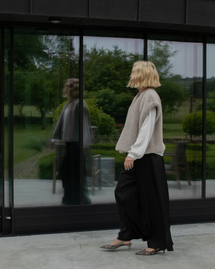 A woman in a white top and shorts is sitting on a couch
