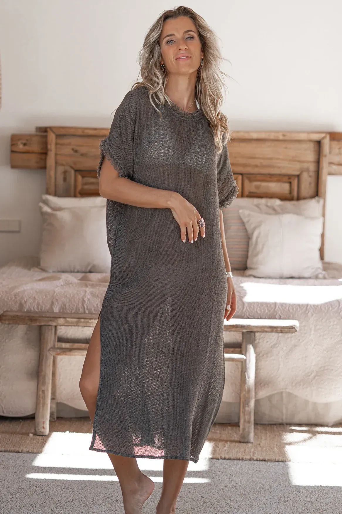 A woman is standing in a room wearing a grey dress.