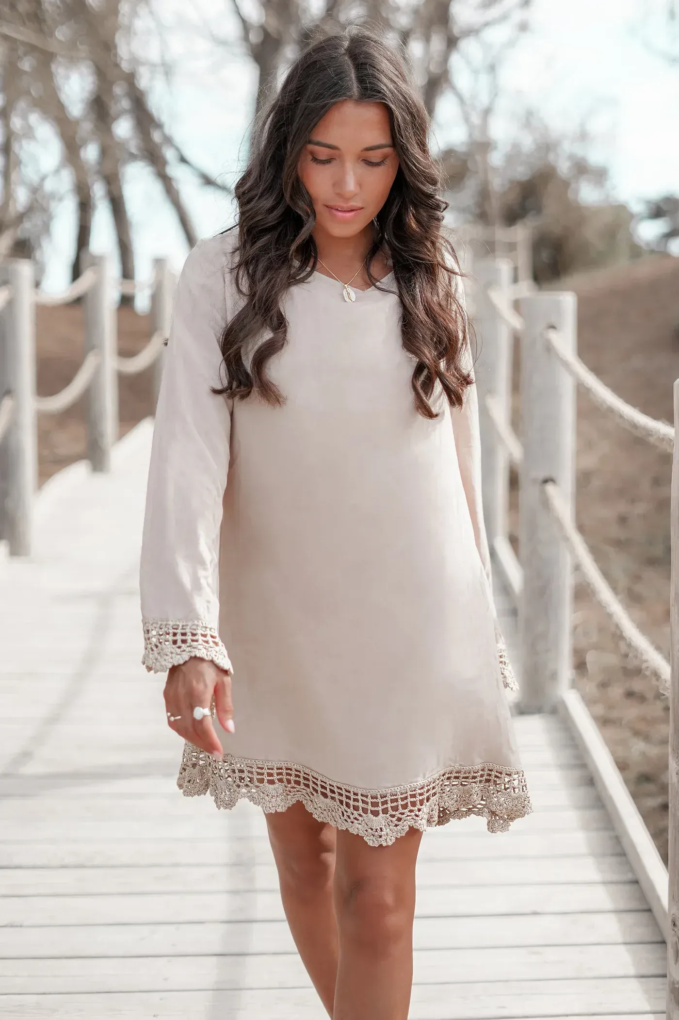 A woman in a white dress is walking on a wooden bridge.