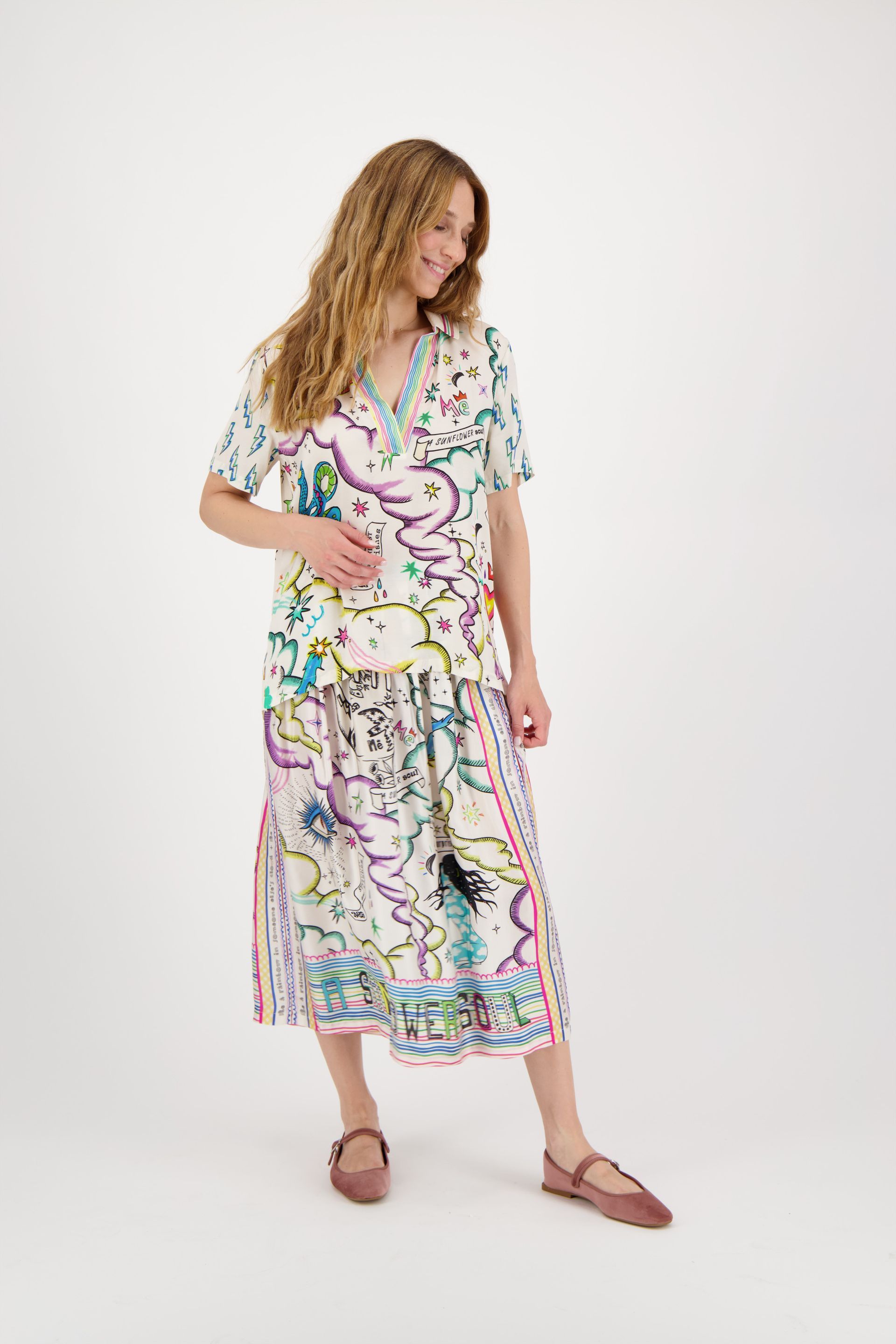 A woman is wearing a white shirt and a colorful skirt.