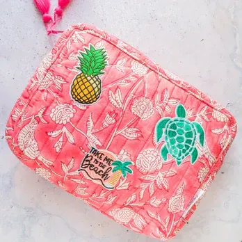 A pink cosmetic bag with pineapples and turtles on it.
