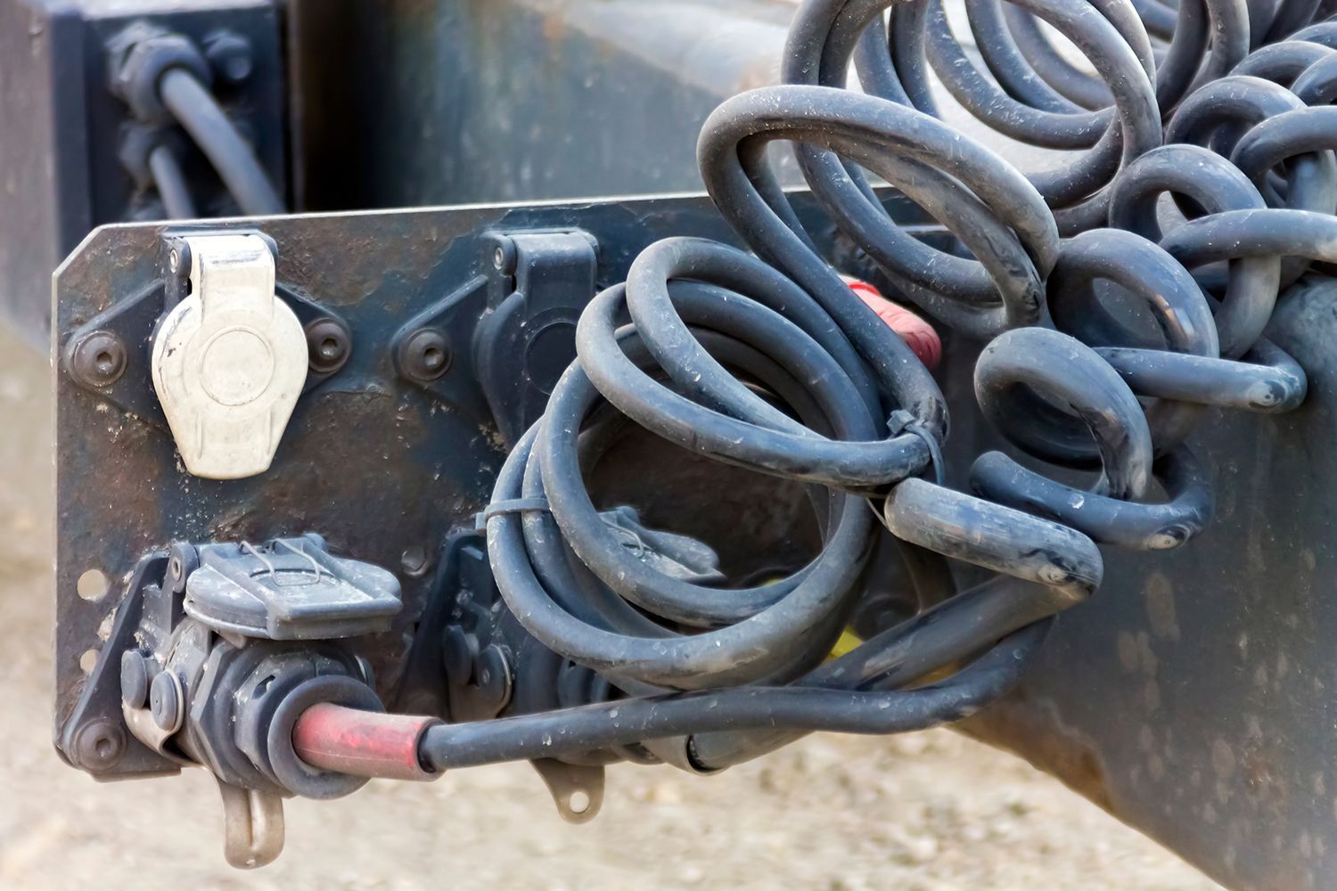 Coiled black cables connected to a weathered metal electrical connector box.