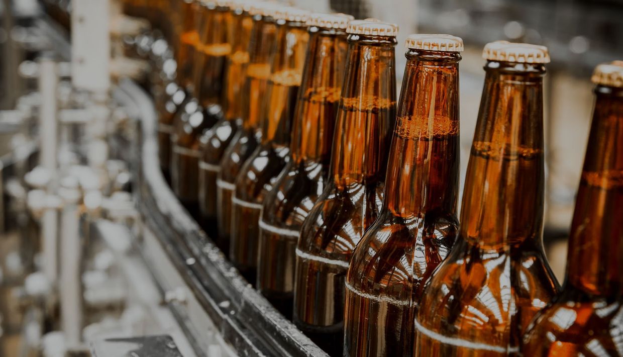 a conveyor belt filled with bottles of beer in a brewery .