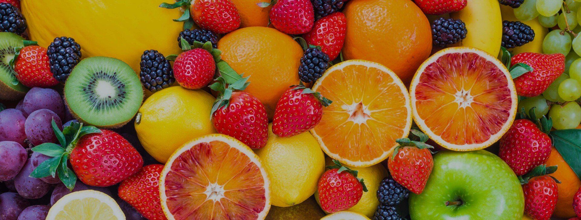 a variety of fruits and berries are sitting on top of each other on a table .