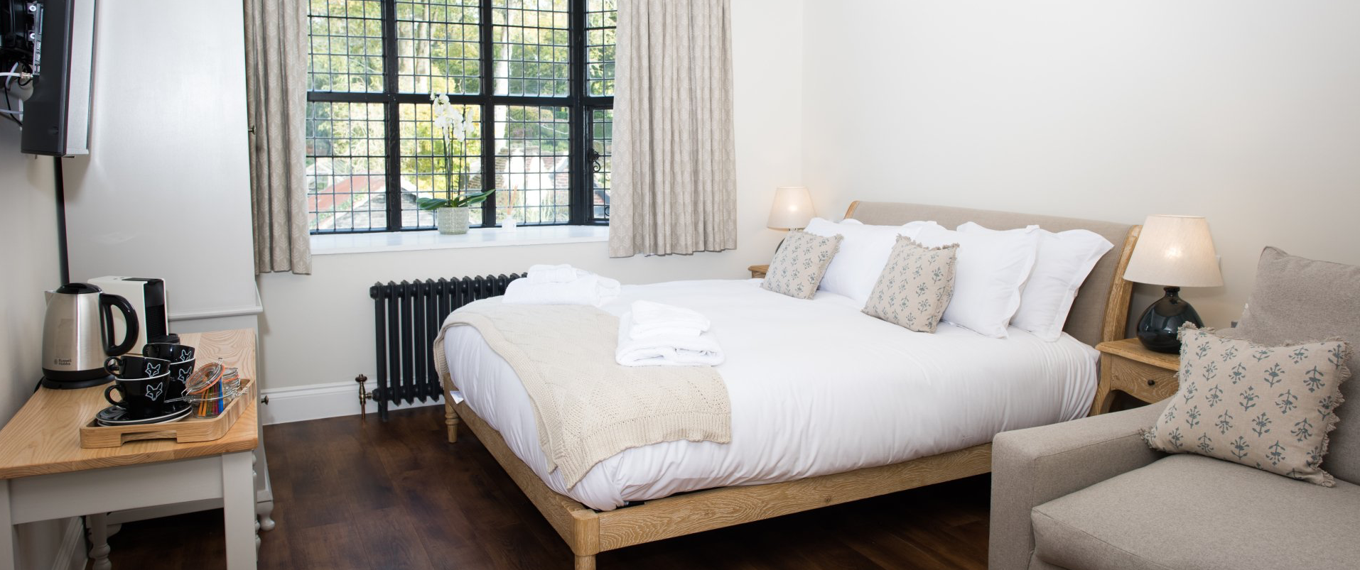 A hotel room with a bed , chair , table and window