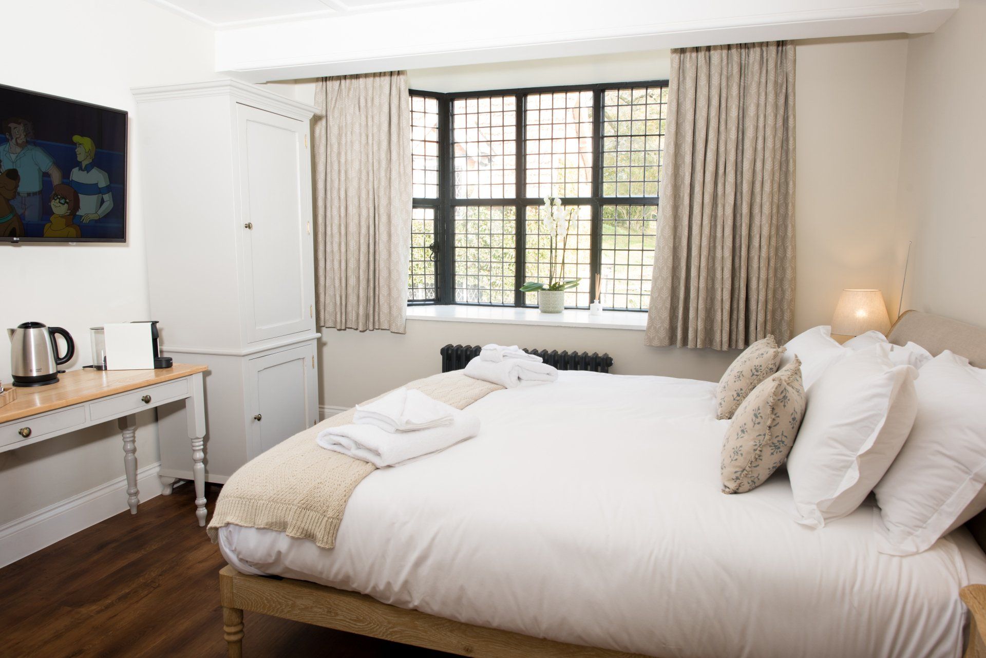 A bedroom with a king size bed and a large window.