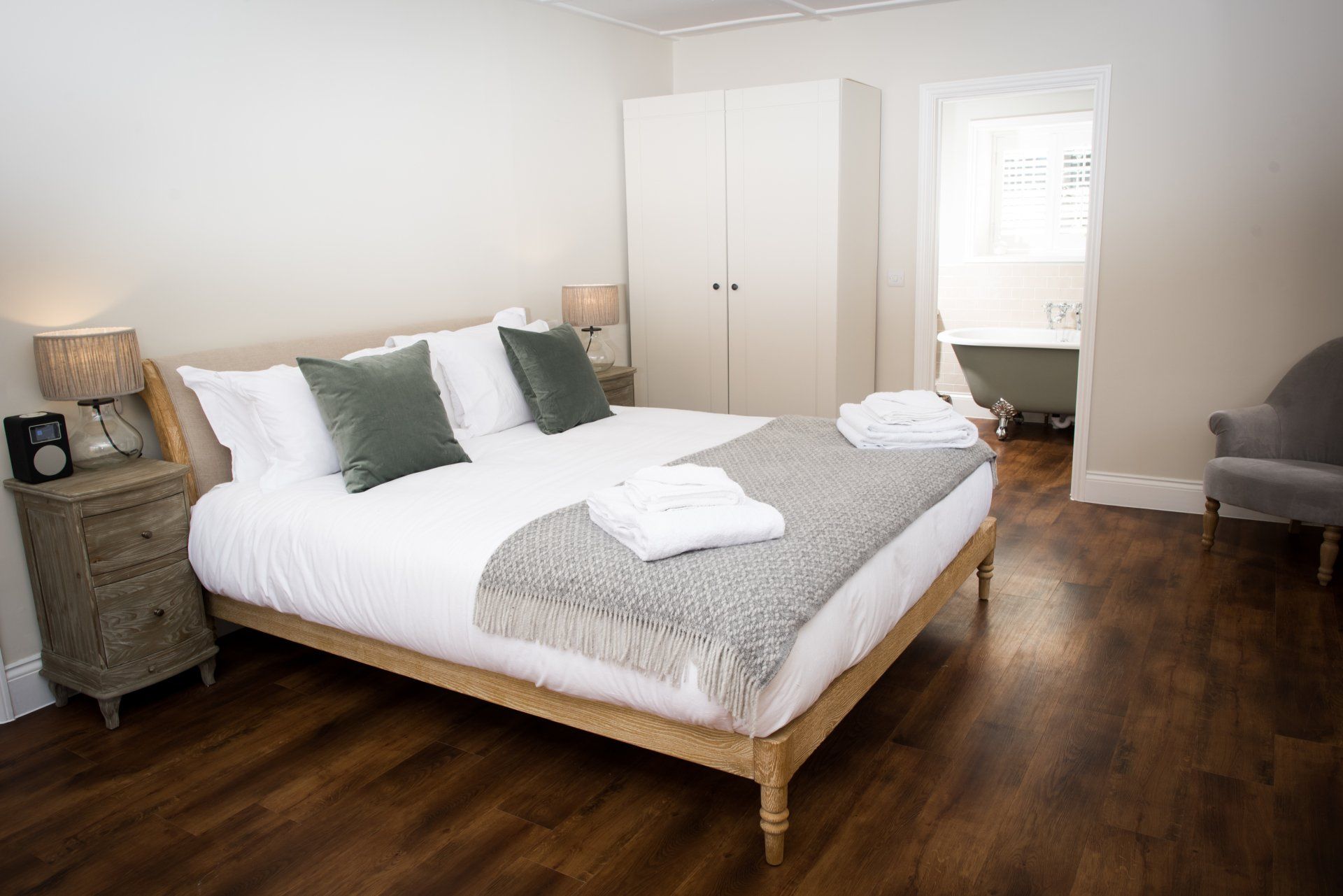 A bedroom with a king size bed , nightstand , chair and bathtub.