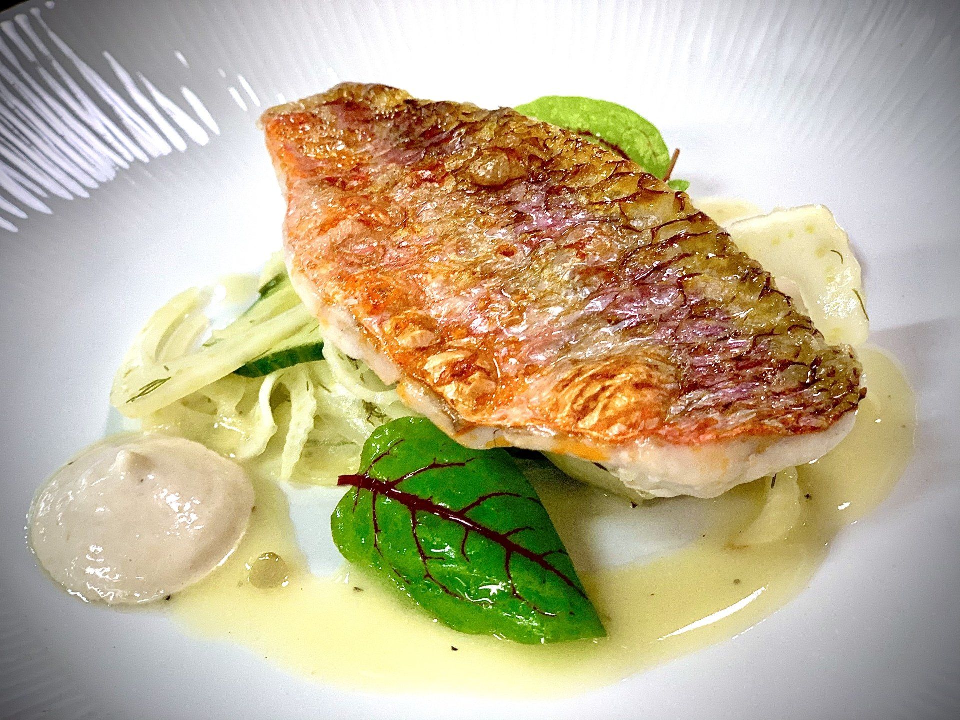 a white plate topped with a piece of fish and vegetables .