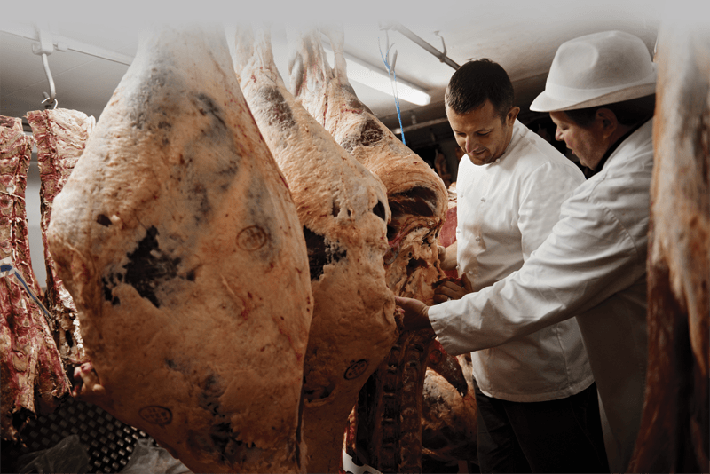 two butchers preparing a large piece of meat