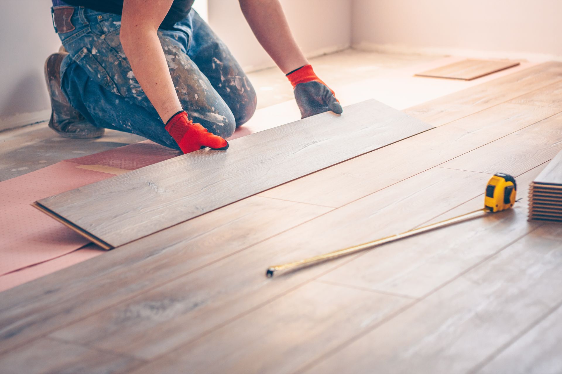 Un homme installe un parquet dans une pièce.
