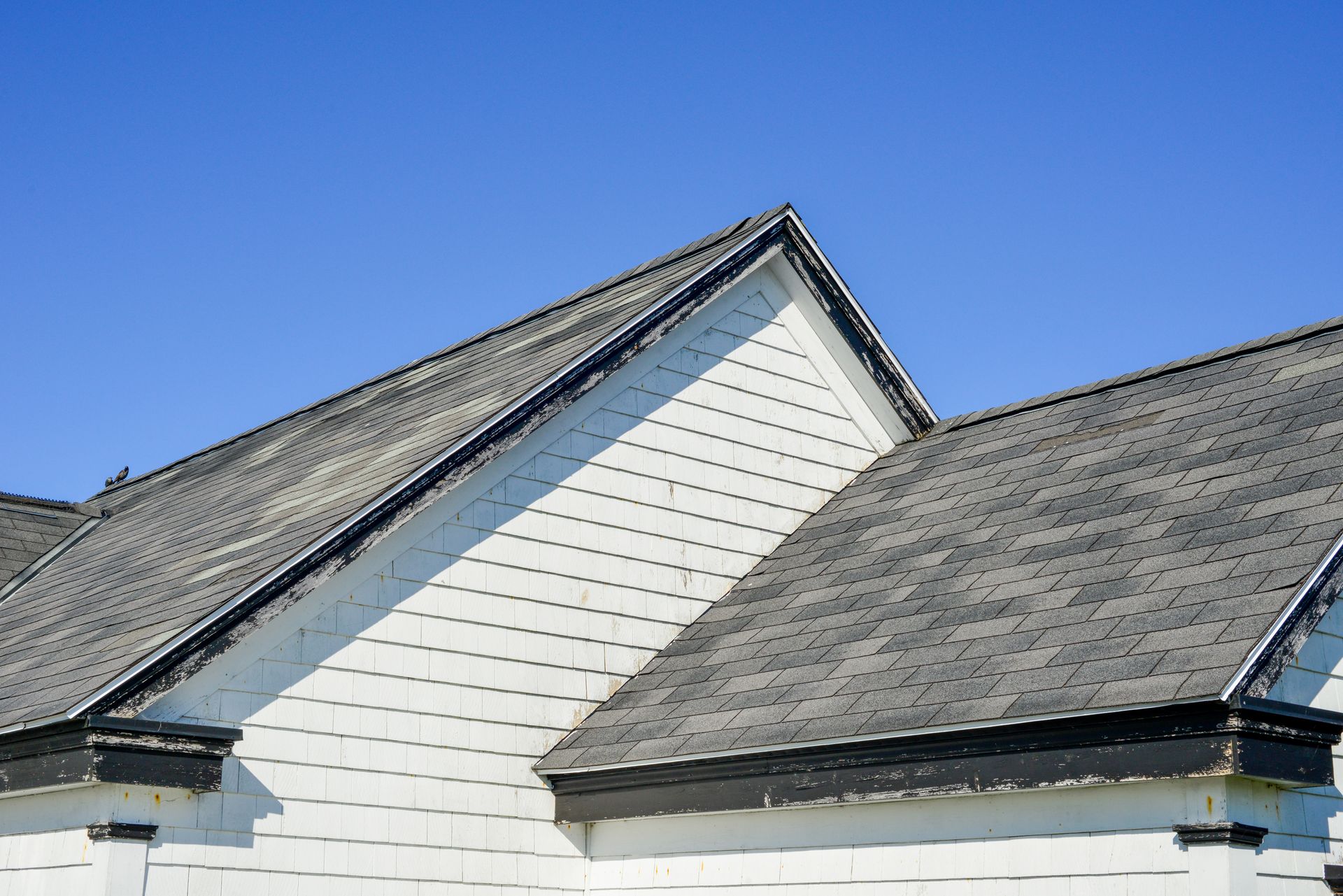 Une maison blanche avec un toit gris et un ciel bleu en arrière-plan