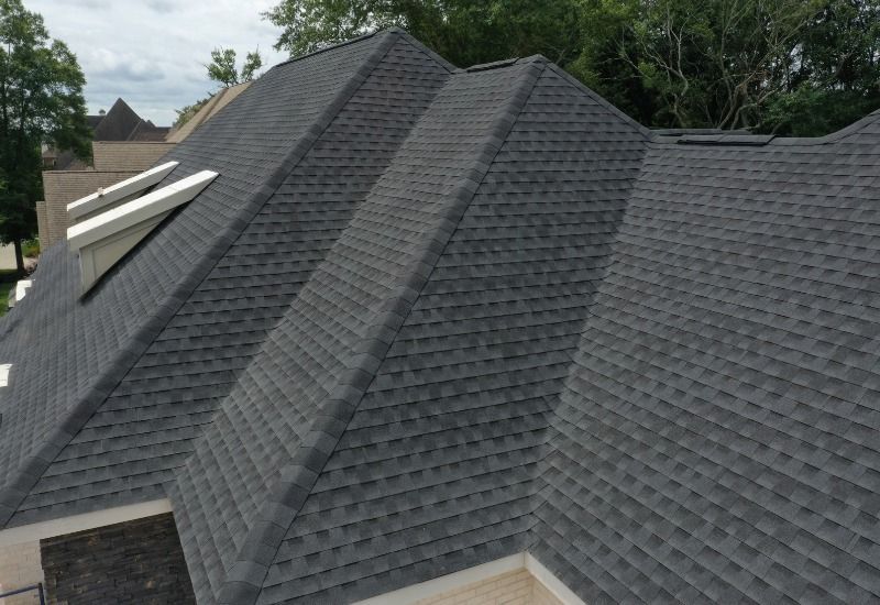 Dark gray asphalt shingle roof with multiple gabled sections. Skylights visible.