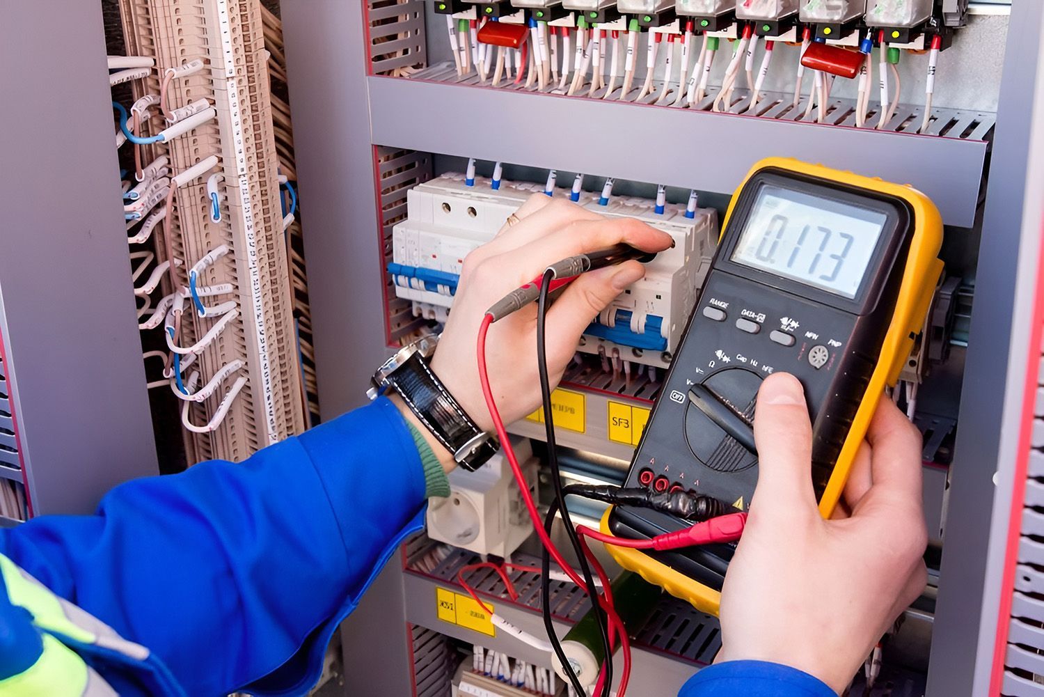 Electrician Using A Multimeter To Test Wiring Inside A Control Panel