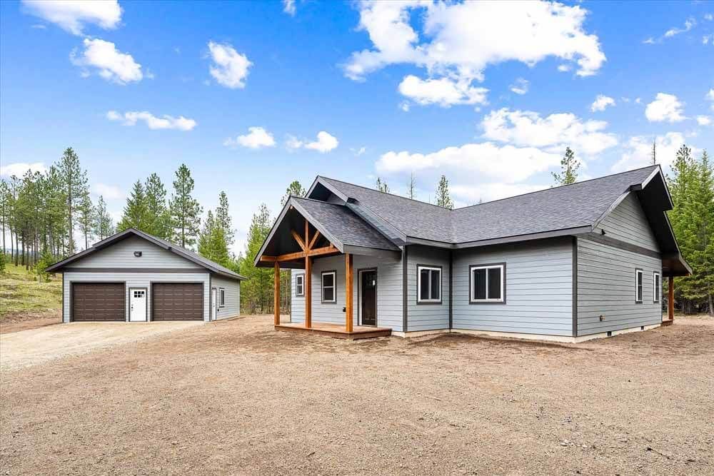A large house with a garage next to it in the middle of a dirt field.