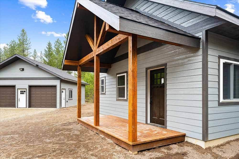A small house with a porch and a garage next to it.