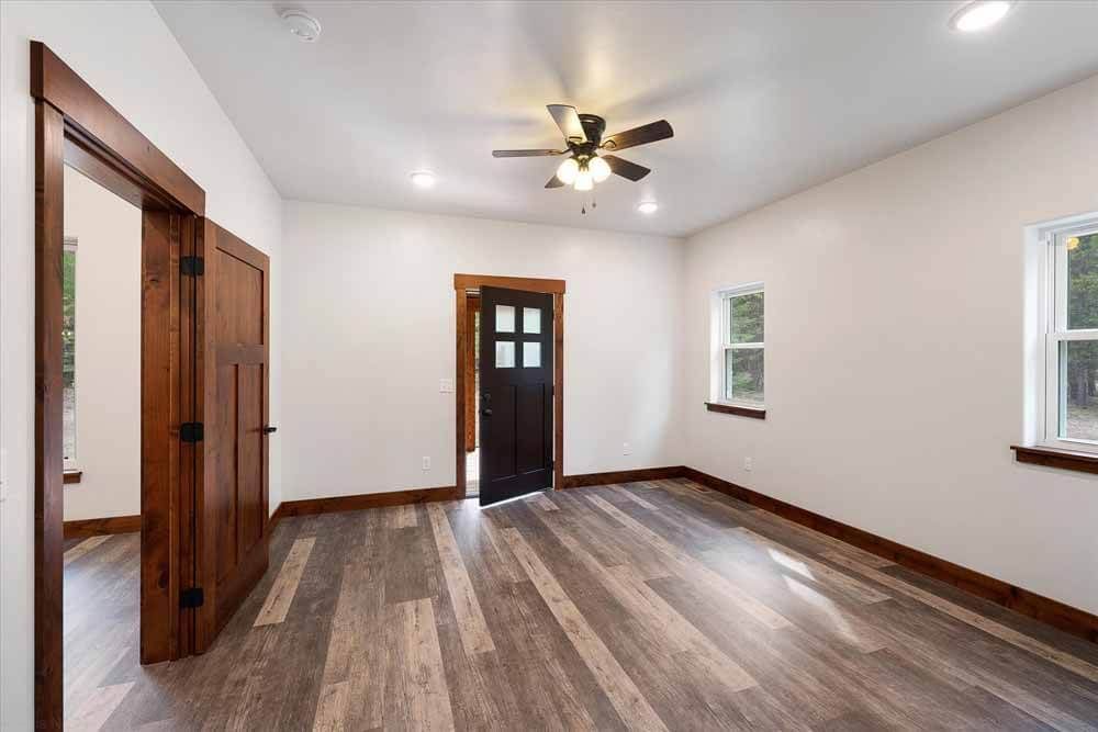 An empty room with hardwood floors and a ceiling fan.