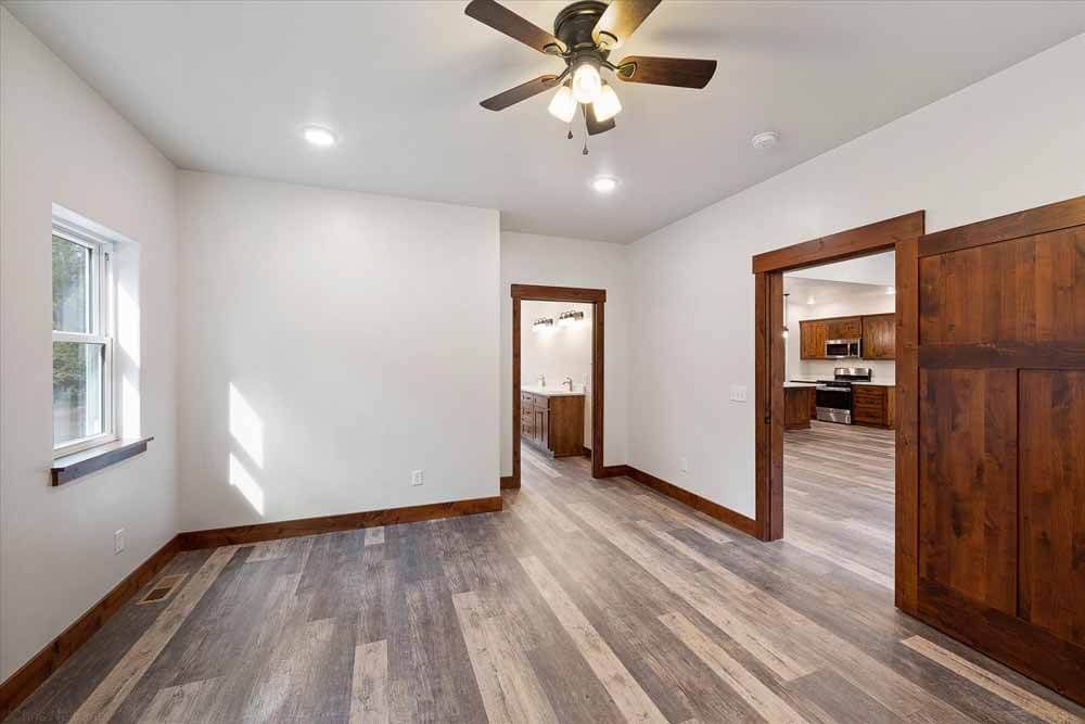 An empty living room with hardwood floors and a ceiling fan.