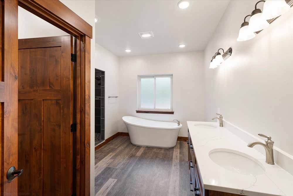 A bathroom with two sinks, a tub, and a window.