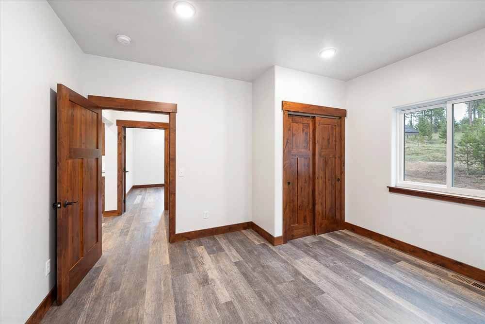 An empty bedroom with hardwood floors and a window.