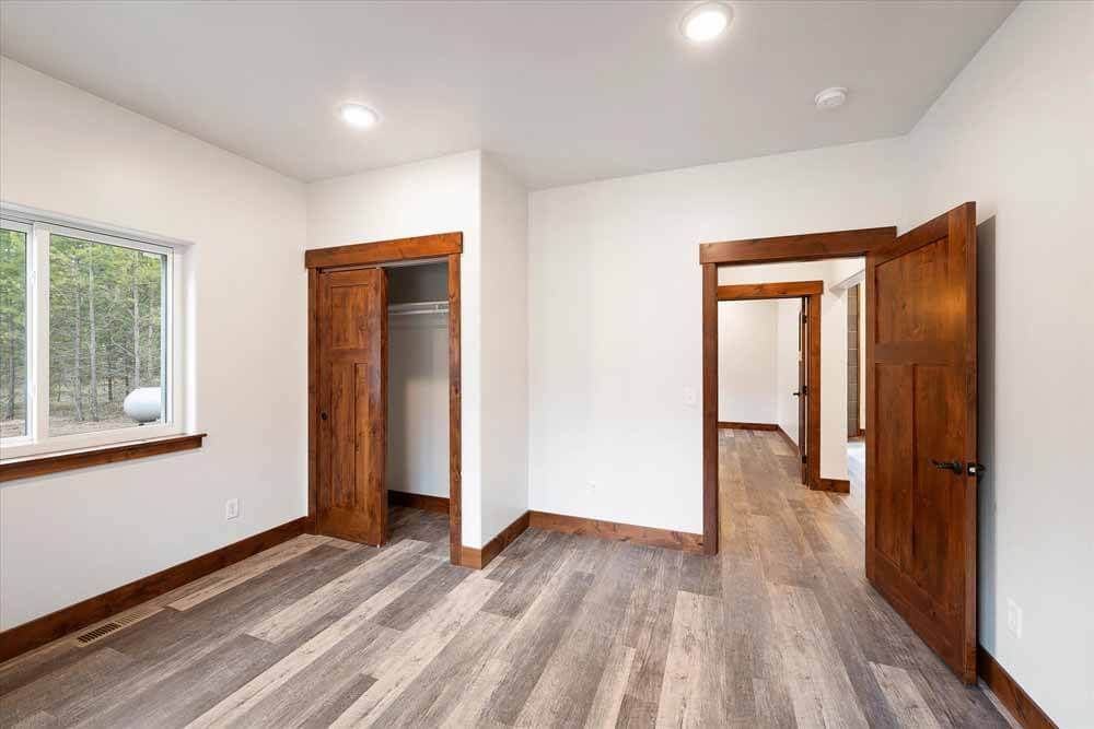 An empty bedroom with hardwood floors and a closet.