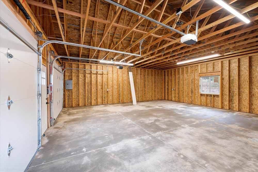 An empty garage with a garage door and a window.