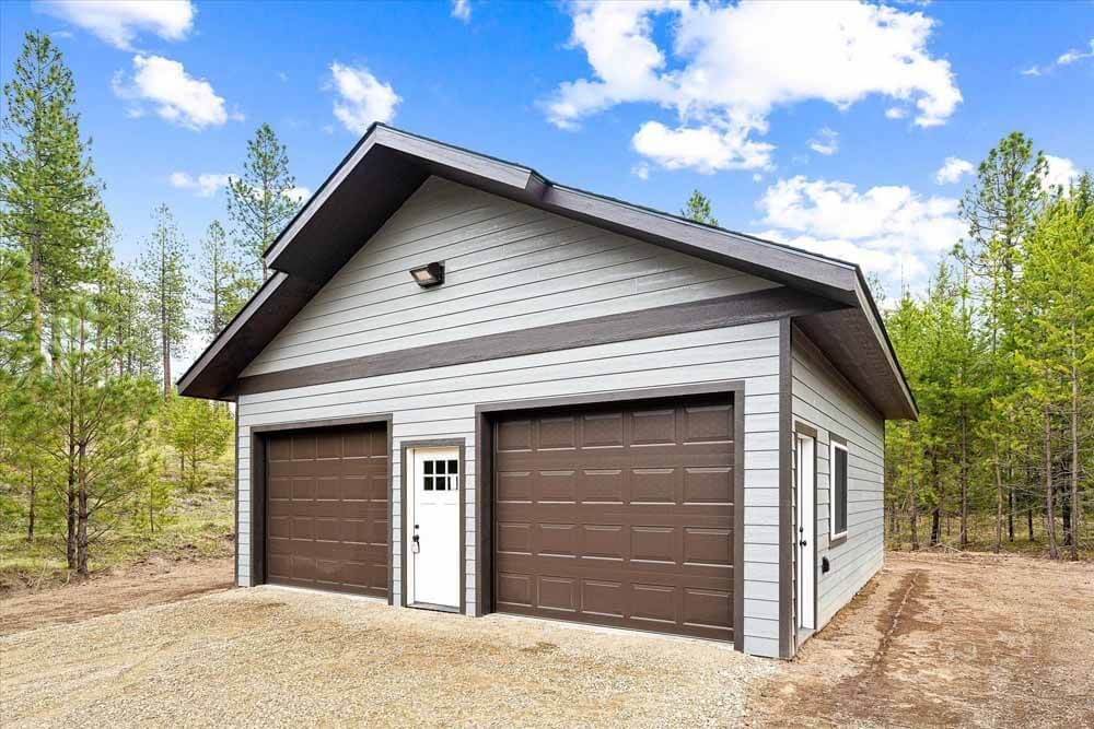 A white garage with two brown garage doors.
