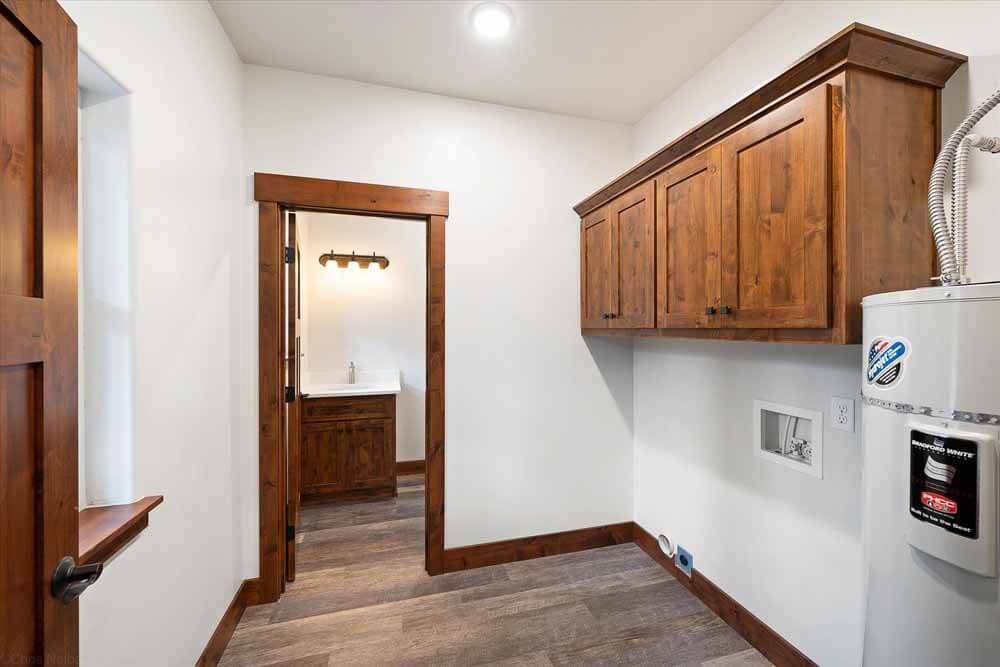 A laundry room with wooden cabinets and a water heater.