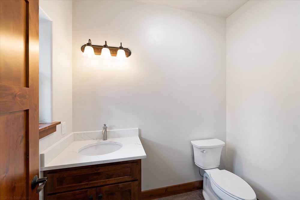 A bathroom with a sink, toilet, and light fixture.