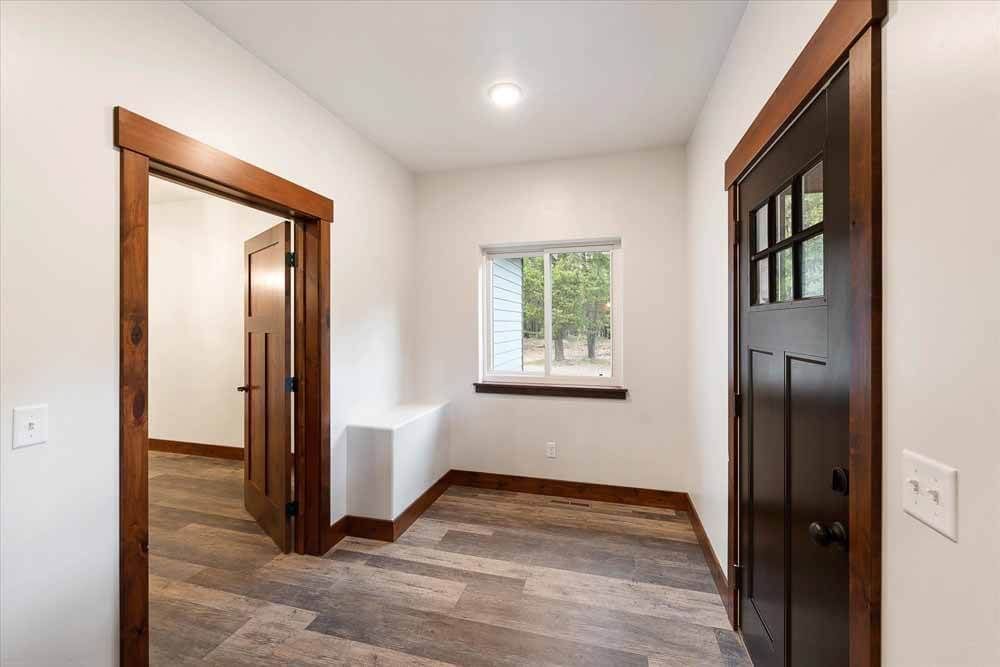A hallway in a house with wooden floors and a window.