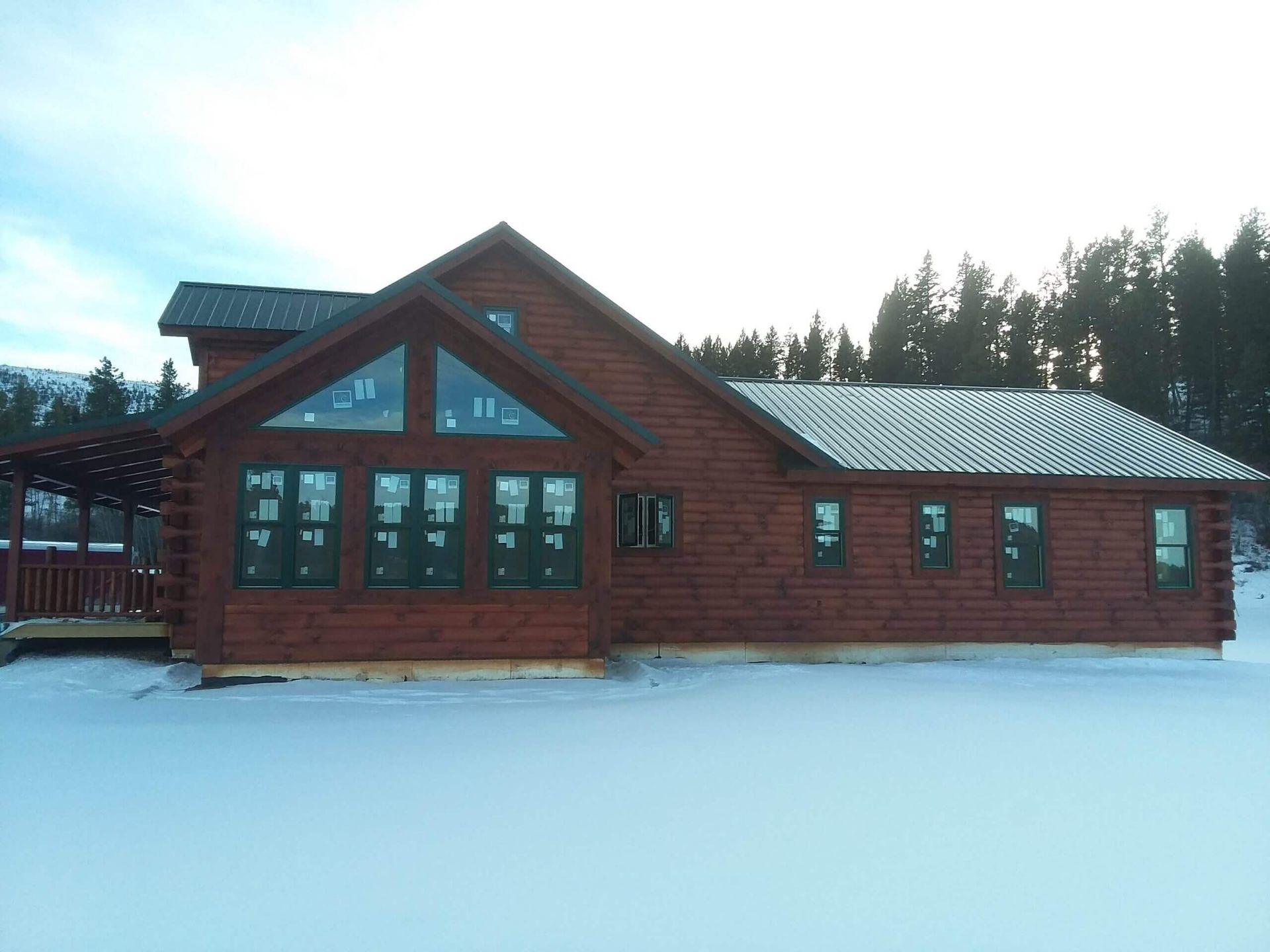 A large log cabin is sitting in the middle of a snowy field.
