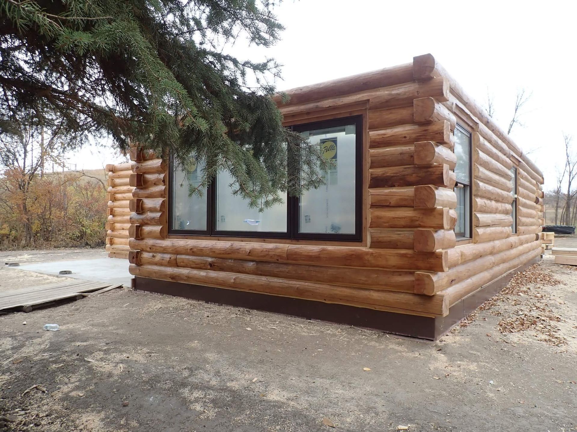 A log cabin with a tree in front of it