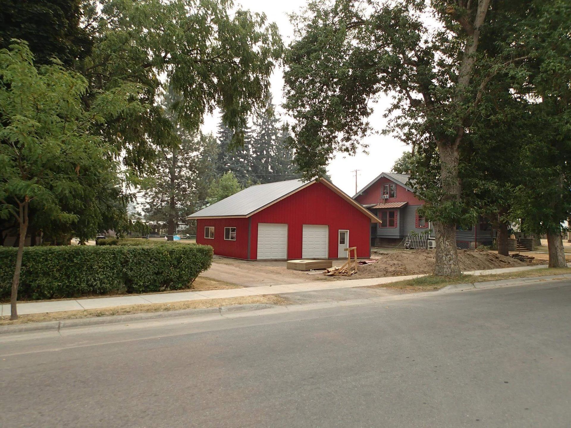 A red garage with white doors sits next to a house
