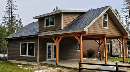 A small house with a porch and a fence in front of it.