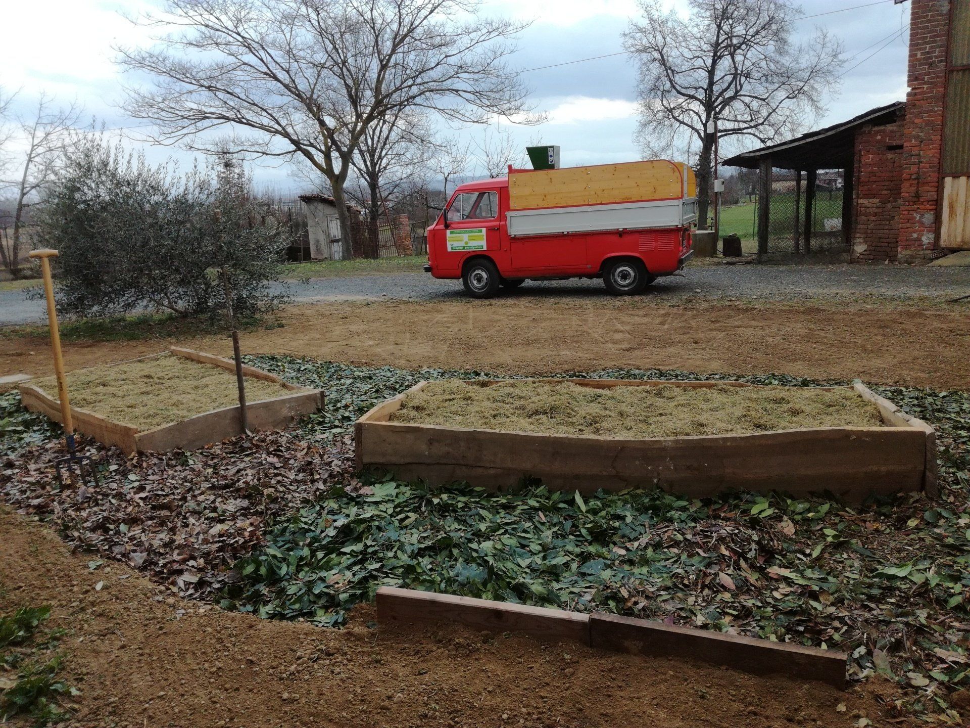 Aiule rialzate con pacciame, piccolo camion rosso e giallo e alberi.