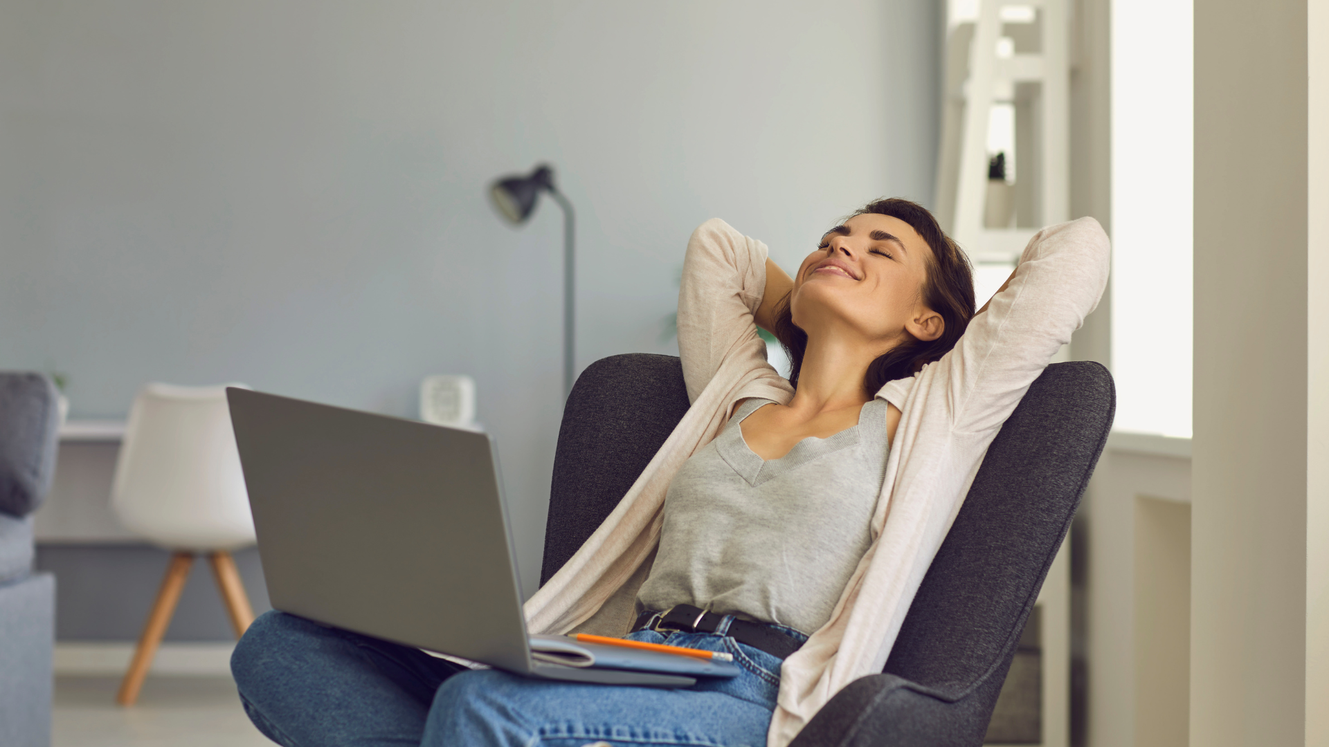 A woman is sitting in a chair with a laptop.