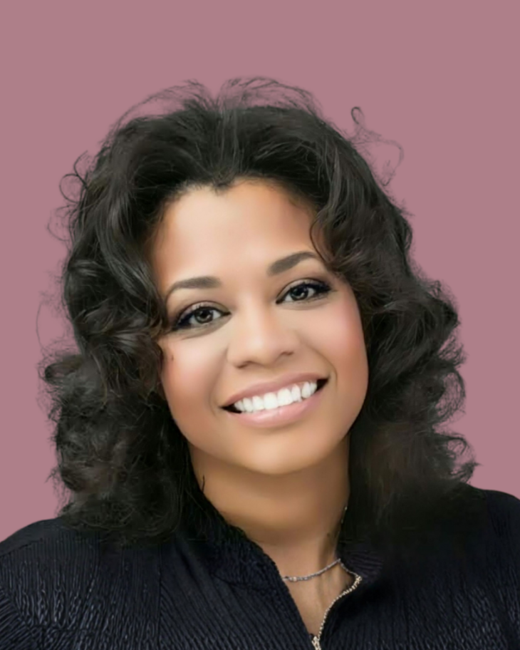 Woman with curly dark hair smiles, looking at the camera.