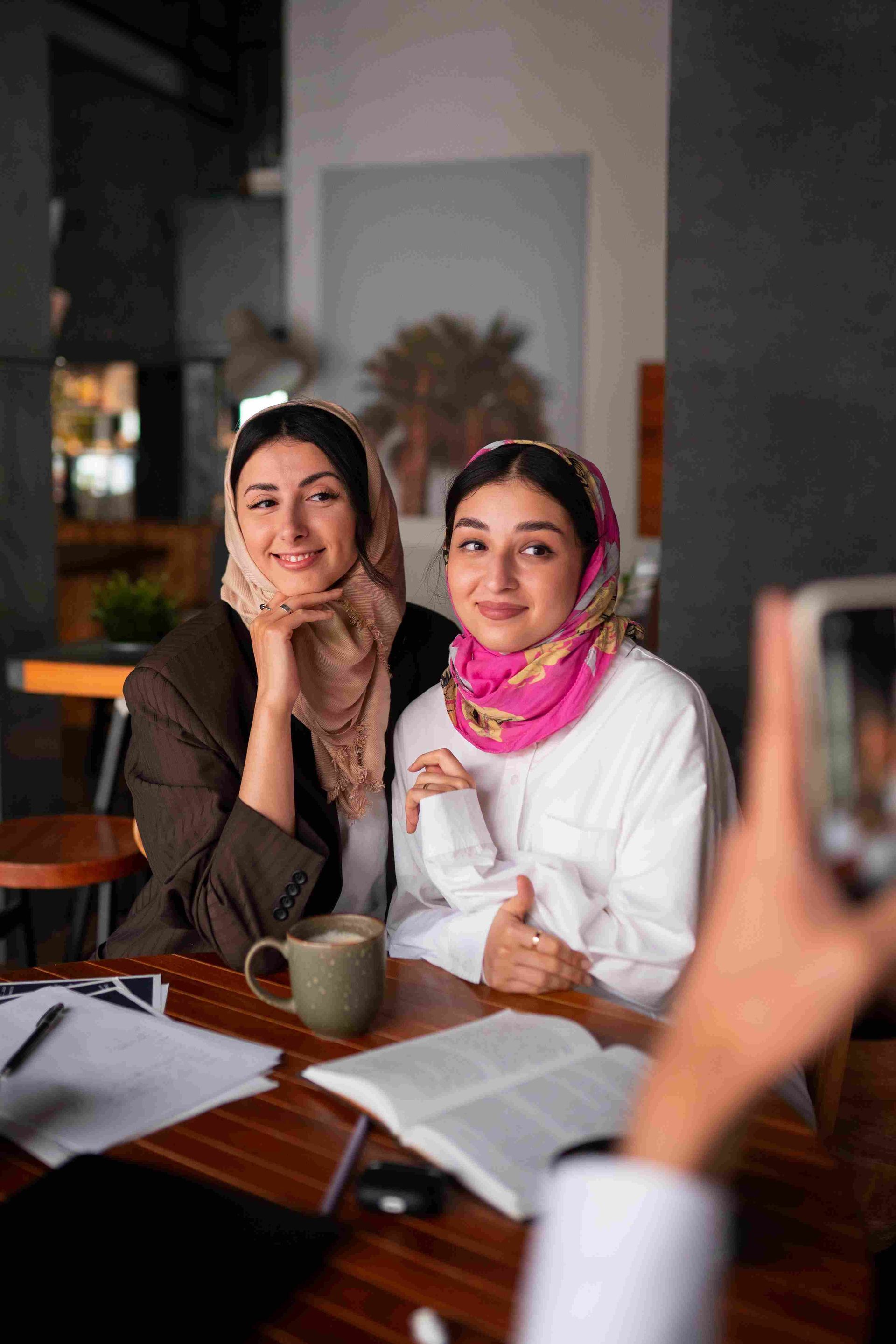 A woman is taking a picture of two women sitting at a table.