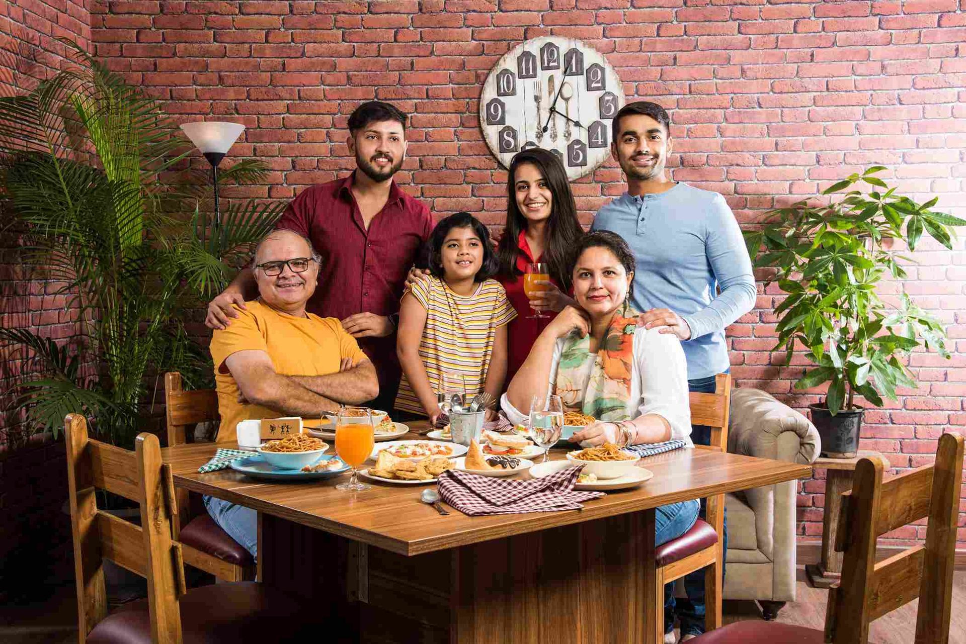 A family is posing for a picture while sitting at a dining table.