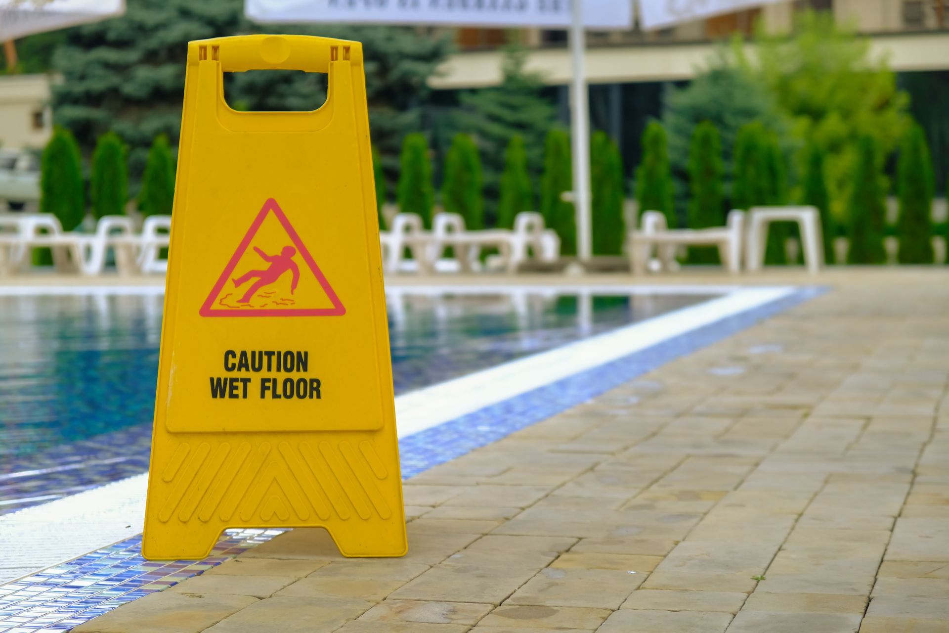 caution wet floor sign in front of swimming pool 