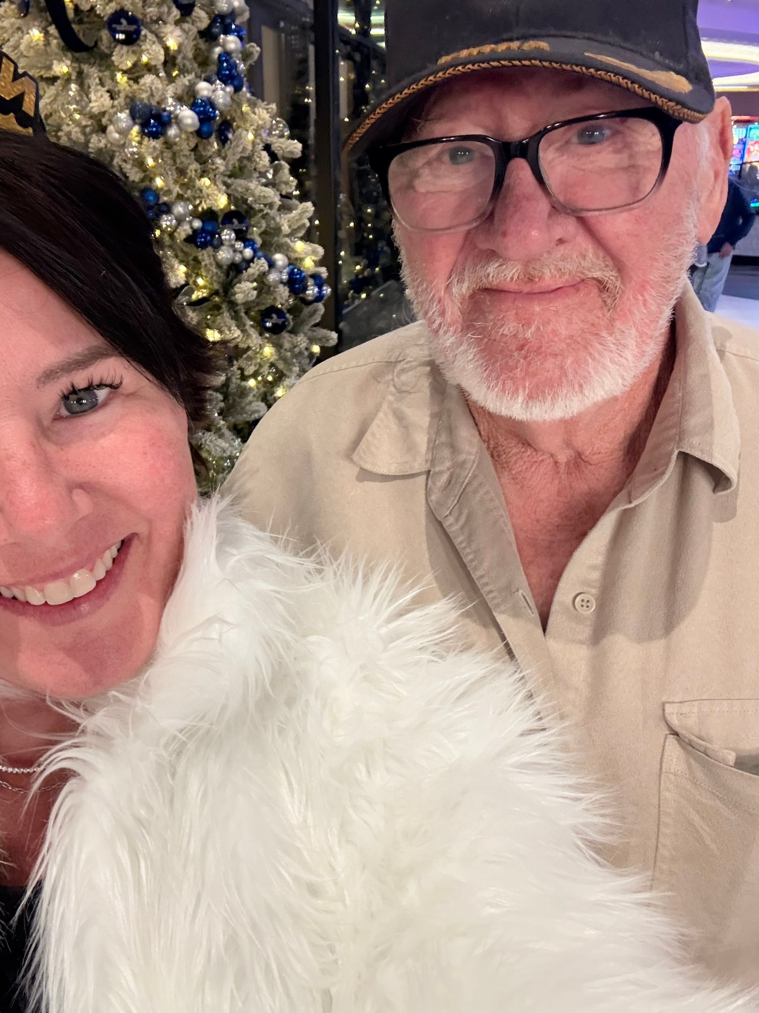 A cozy  moment, smiling couple near a glowing Christmas tree at Grand Island Casino Resort.