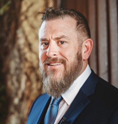 A man with a beard is wearing a suit and tie.