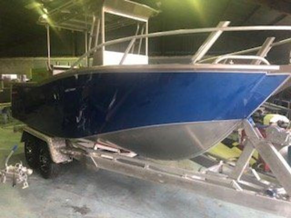 A blue boat is on a trailer in a garage.