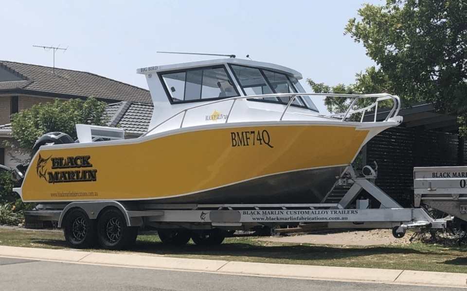 A yellow and white boat is parked on a trailer.