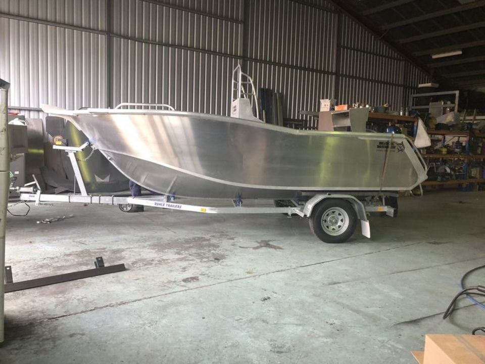 A boat is sitting on a trailer in a warehouse.